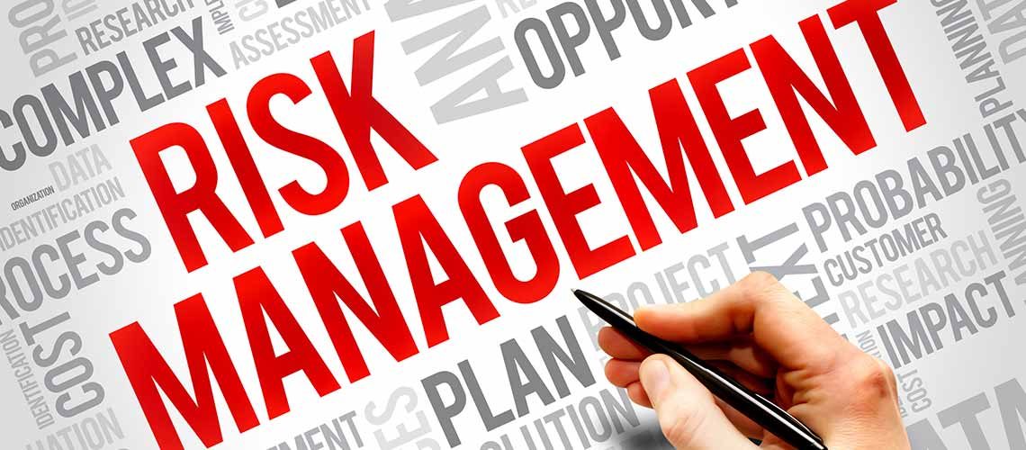 Risk Management in red type with hand and pen